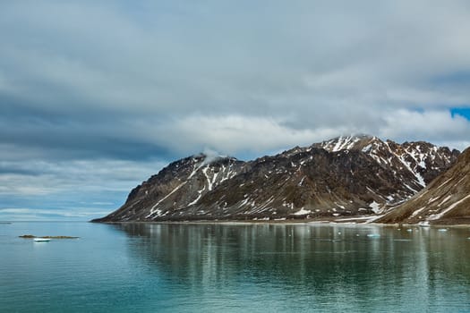 Cloudy sky and mountains along the Magdalenafjord in Svalbard islands, Norway