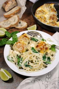 Spaghetti with chicken meatballs in cheese cream sauce , spinach and capers
