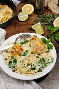 Spaghetti with chicken meatballs in cheese cream sauce , spinach and capers