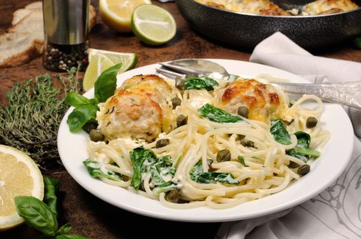 Spaghetti with chicken meatballs in cheese cream sauce , spinach and capers
