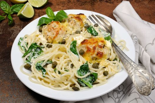 Spaghetti with chicken meatballs in cheese cream sauce , spinach and capers