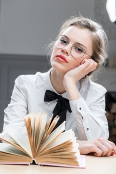 portrait of a dreamy girl with glasses with a book