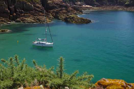 A sailboat at anchor in Portelet bay, Jersey, UK. Turquoise water and sunshine. Horizontal format