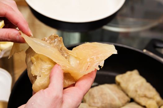 Preparation of cabbage rolls.  Woman lays minced meat in cabbage leaves.
