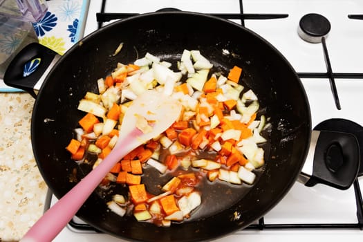 Roasting finely chopped onions and carrots in a pan.