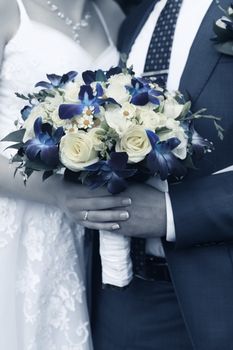 Hand of the groom and the bride with wedding bouquet