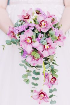 Wedding bouquet in the hands of the bride. Round wedding bouquet of pink flowers.