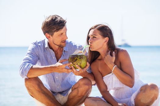 Young couple enjoying their time drinking a coconut cocktail on beach