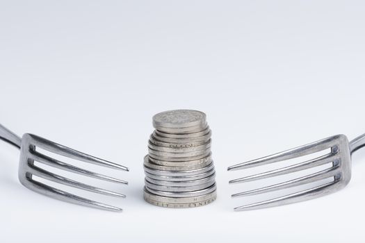 Conceptual representation of financial greed by two forks and coins
