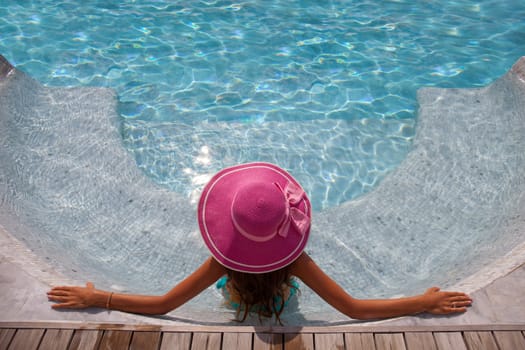 Beautiful woman relaxing at swimming pool at tourist resort