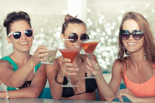 Happy young women with beverages having fun in cafe