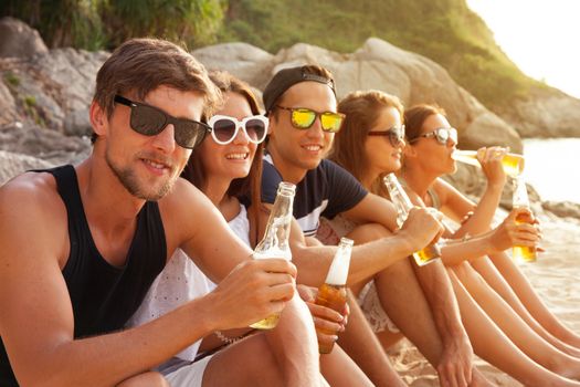 Happy young friends drinking beer outdoors