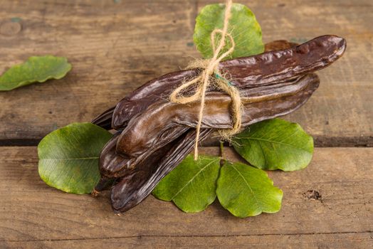 Raw fruits Carob on old wooden background