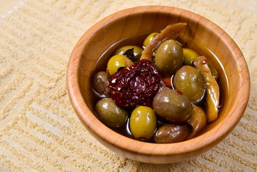 Bowl filled with freshly harvested whole fresh green olives on a wooden tabletop.