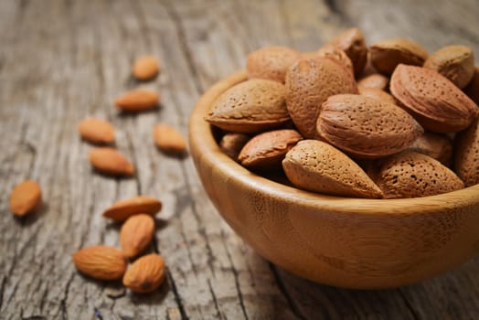 Almonds in a wooden bowl on a rustic brown table