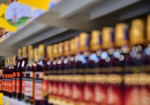 Blurred section bottles of spirit, hard liquor at retail store in Europe. Aisle in local supermarket, defocused background.