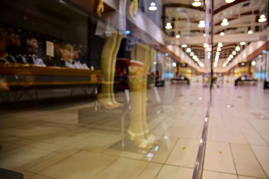 Blurred shop windows at retail store in Europe. Corridor in local supermarket, defocused background. Fashion clothes retail store sale display with female woman mannequin.