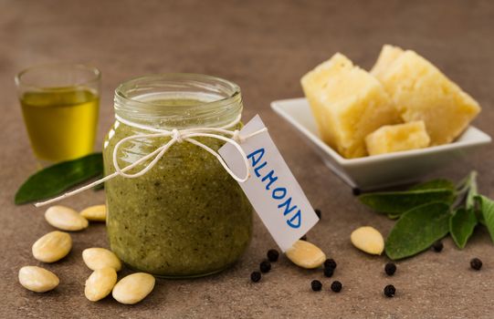 Pesto with almonds and pecorino cheese in a glass jar on a wooden table