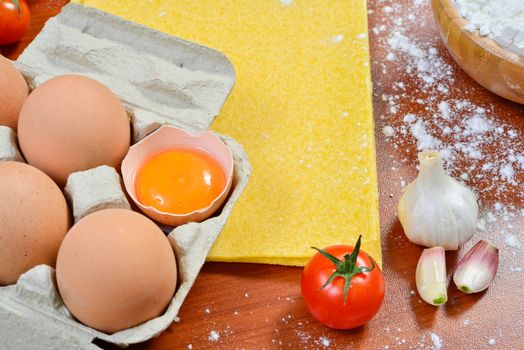 Egg noodles with ingredients on wooden table.