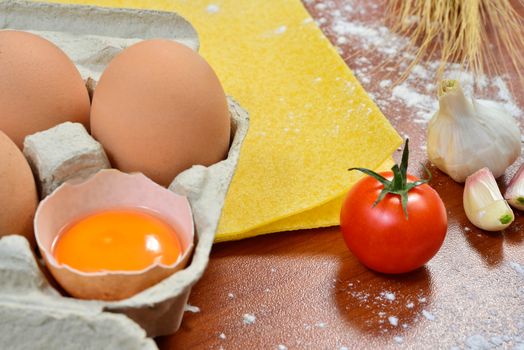 Egg noodles with ingredients on wooden table.
