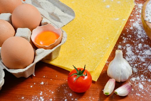 Egg noodles with ingredients on wooden table.