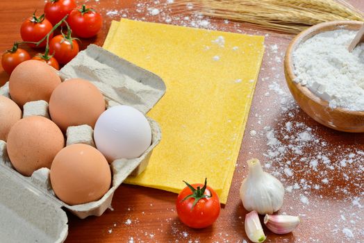 Egg noodles with ingredients on wooden table.