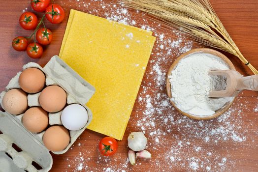 Egg noodles with ingredients on wooden table.