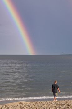 A young boy and rainbow on the beach in Maine, Usa
