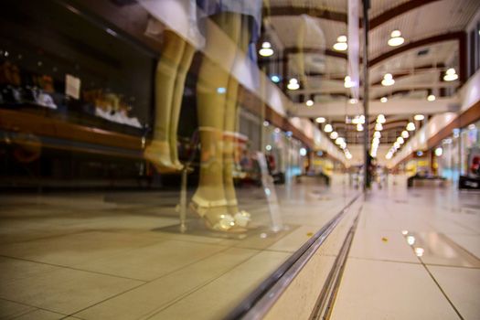 Blurred shop windows at retail store in Europe. Corridor in local supermarket, defocused background. Fashion clothes retail store sale display with female woman mannequin.