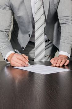 Businessman signing a contract standing near office desk