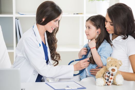 Young smiling female doctor and her little patient with teddy bear