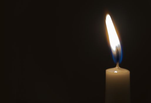 One light candle burning brightly in the black background