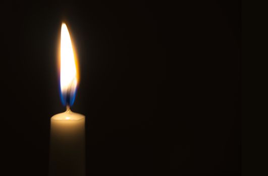 One light candle burning brightly in the black background
