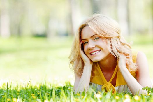 Smilng happy young woman lying on green grass meadow