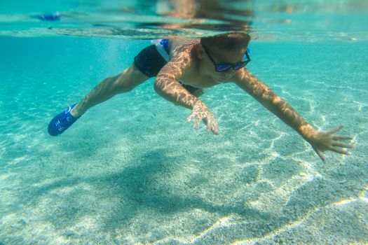 Boy swimming underwater, beautiful view of crystal clear transparent water of Mediterranean sea in Croatia