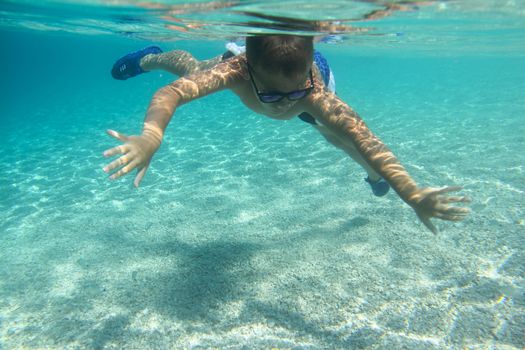 Boy swimming underwater, beautiful view of crystal clear transparent water of Mediterranean sea in Croatia
