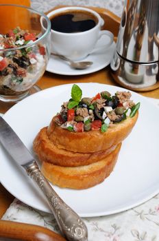Breakfast from fried toast with chopped tuna with egg, cubes of tomatoes and olive slices, capers with a cup of coffee, a coffee pot on a tray