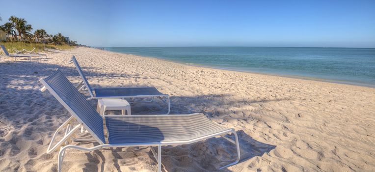 Two beach chairs under a Clear blue sky over Lowdermilk Beach in Naples, Florida