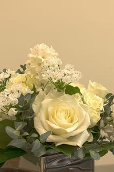 White wedding bouquet of flowers including roses, white lilac, hydrangea, star of David and hyacinth in a reflective mirror vase.