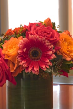 Orange and pink rose and daisy flowers bouquet in a glass vase