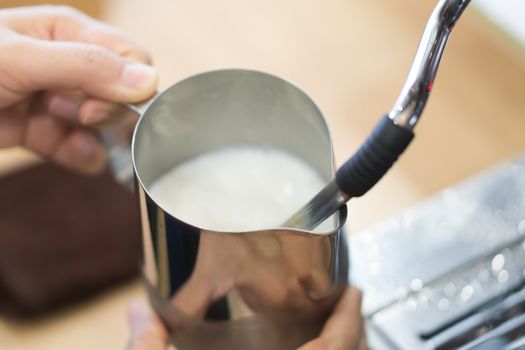Closeup stream milk for make hot coffee latte art with machine, selective and soft focus