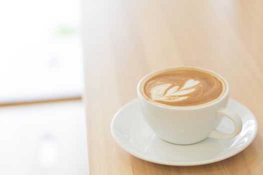 Closeup glass of latte art coffee tulip shape on wood background with vintage color, selective focus