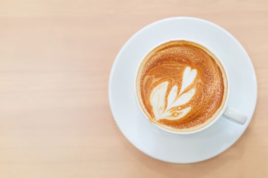 Closeup top view glass of latte art coffee tulip shape on wood background with vintage color, selective focus