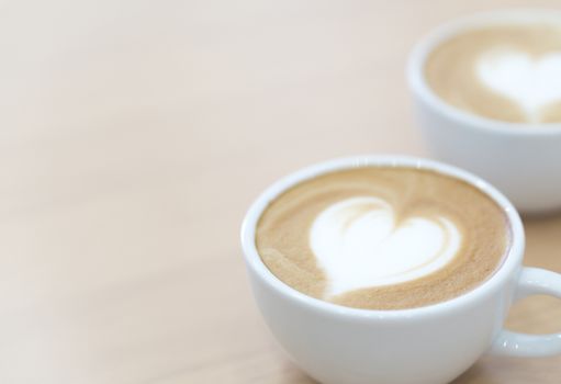 Closeup latte art coffee with heart shape in white cup for relax time and holiday concept, selective and soft focus 
