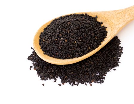 Closeup black sesame seeds on wood spoon with white background, healthy food concept