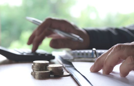 Man using calculator with stock financial indices with stack coin. Financial stock market in accounting market economy analysis.