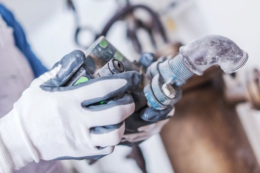 Plumbing Service Work. Plumber with Some Hydraulic System Part in Hand. Closeup Photo