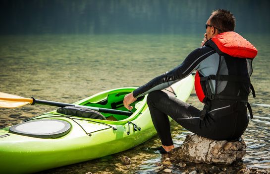 Tour Kayaker and the Lake. Caucasian Men in His 30s and His Green Plastic Kayak. Water Recreation Theme.