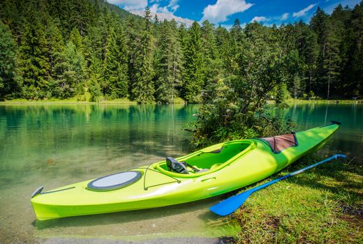 Scenic Kayak Trip. Green Single Kayak on the Shore of Scenic Alpine Lake.