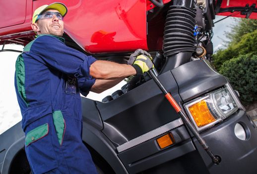 Semi Truck Maintenance by Professional Truck Mechanic. Caucasian Technician Preparing Truck Cabin For the Scheduled Engine Service.